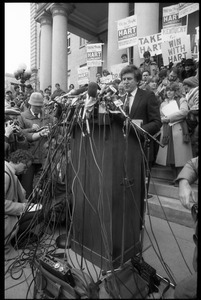 Gary Hart at a microphone-encrusted podium, addressing an crowd after renewing his bid for the Democratic nomination for the presidency