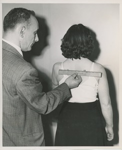 Man measuring woman's back for prosthesis fitting