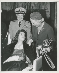 Young woman in wheelchair talks with woman and man in navy uniform