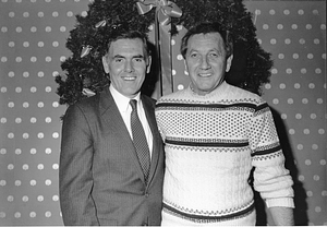 Mayor Raymond L. Flynn posing in front of Christmas wreath with an unidentified man
