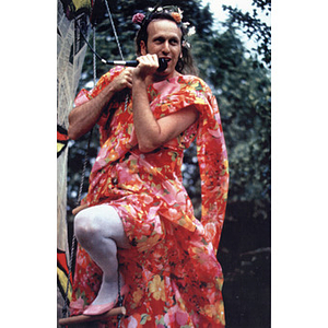 Abe Rybeck, dressed in costume on a ladder, speaking into a microphone