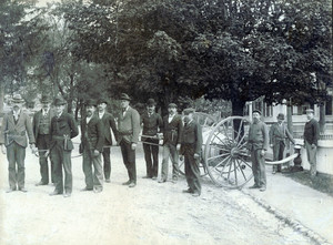 Firefighters holding a hose attached to a street hydrant, undated