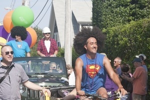 Parade marcher on bicycle, wearing a Superman t-shirt : Provincetown Carnival parade