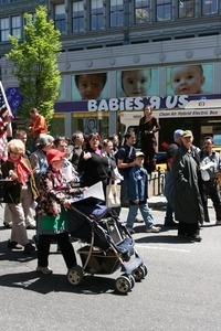 Marcher pushing child in a stroller past the Babies R Us store during the protest against the war in Iraq