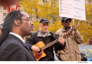 Occupy Wall Street: demonstrator plays guitar in between man in suit and man holding picket sign