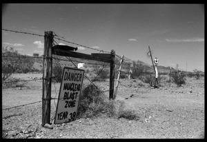 Barbed wire fence with sign (hand-edited) reading 'Danger nuclear blast zone year 38': Nevada Test Site peace encampment