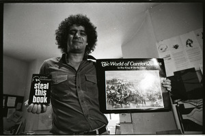 Abbie Hoffman holding copies of Steal This Book and The World of Currier and Ives