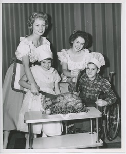 Women performers carving turkey with young clients