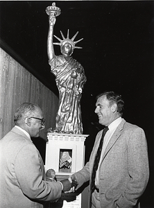 Mayor Raymond L. Flynn and an unidentified man in front of a replica of the Statue of Liberty