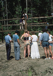 People in front of barn frame with Peter Jensen installing a beam at the Moon Barn Raising at entrance to Hopkins Forest on 2 August 1975.