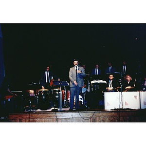 Man addressing the audience at a concert that featured the Harvard Jazz Band and the Cuban musician Mario Bauza.