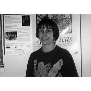 Portrait of a woman with short hair and long earrings standing in front of a poster.