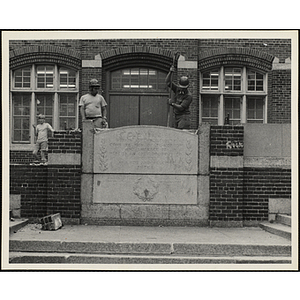 Two workers removing the memorial stone outside the Charlestown Boys' Club at 15 Green Street during the renovation