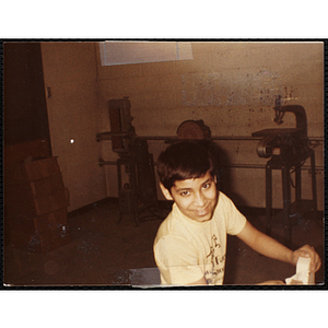 A boy looks at the camera while working on a project for his woodworking class at the Boys and Girls Club