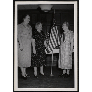 Three women pose with an American flag during a Mothers' Club event