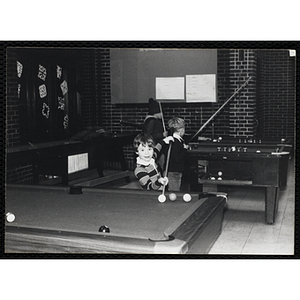 A Young boy prepares to take his shot at a pool table