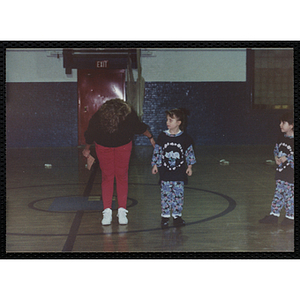 A Woman speaking with two young girls in the gymnasium