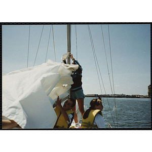 A woman and two children adjust the rigging on a sailboat in Boston Harbor
