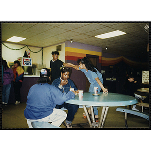 A group of youth eat pizza at a Tri-Club trip to Roller World