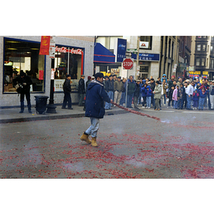 Man swings a strand of firecrackers in the street during a celebration of the Chinese New Year in Boston's Chinatown