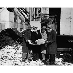 Four men study plans for the Ell Student Center during the ground breaking ceremony