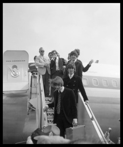 Ringo Starr, George Harrison, and Paul McCartney descending the ramp from a Pan American airways Boeing 707 (John Lennon barely visible behind McCartney)