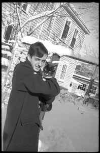 Charles Frizzell holding a tuxedo cat outside after a heavy snow