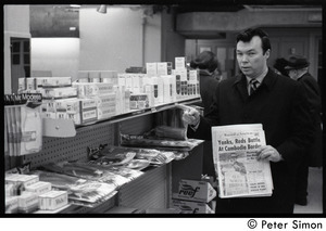 Bill Baird, contraception rights advocate, at a pharmacy, holding up the day's newspaper next to supplies
