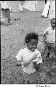 Young girl with playing with sticks, with a boy in the background