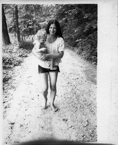 Nina Keller carrying baby Eben Light down the road, Montague Farm Commune