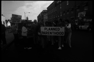 Planned Parenthood escorts with banner passing pro-life protesters in front of the Providence Planned Parenthood clinic