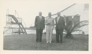 Three unidentified men standing outside near an airfield