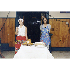 Two women stand next to a table of food at the Festival Puertorriqueño