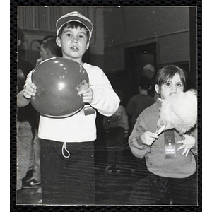 A boy holding a rubber ball while a girl stands beside him and eats cotton candy at a joint Charlestown Boys and Girls Club and Charlestown Against Drugs (CHAD) event