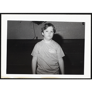 A boy wearing a t-shirt with "Boys' Club of Boston Day Camp" logo and posing at the South Boston Boys & Girls Club