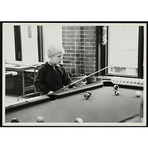 A Young boy prepares to take his turn in a billiards game