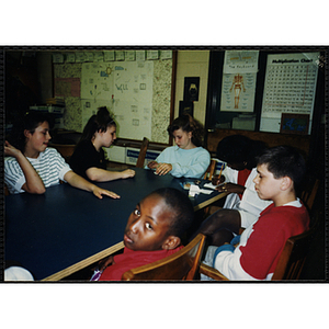 Children sit at a table with site coordinator Sheila Wood at the Tri-Club youth leadership event at the Roxbury Clubhouse