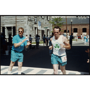 A man crosses the finish line as he is cheered on by a race official during the Battle of Bunker Hill Road Race