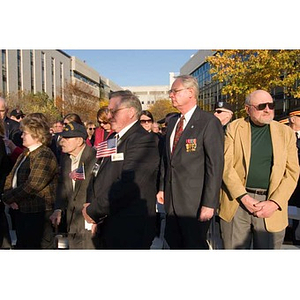 Several men stand in the audience at the Veterans Memorial dedication