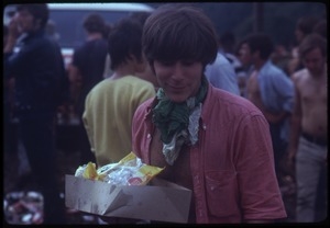 Young man with a scarf around his neck and a box of snacks during the Woodstock Festival
