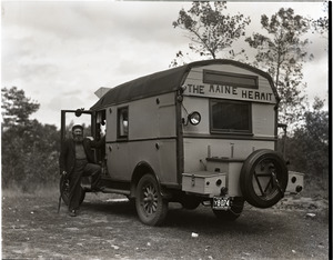 Charles Coffin, The Maine Hermit, posed with his bus with sign "Maine Hermit" (view from rear)