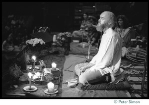 Ram Dass seated onstage at the Winterland Ballroom during his 'marathon,' looking out toward the audience