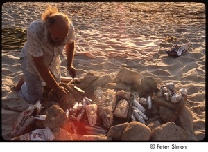 Ram Dass cooking fish and corn over an open fire on the beach