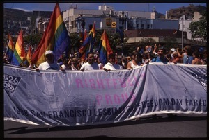 Massive crowd approaching during the San Francisco Pride Parade, carrying pride flags and banner reading 'Rightfully proud'