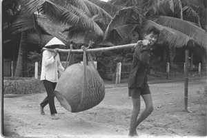 Farmer leaving village transporting water jars after Vietcong attack; Luong Hoa Village.