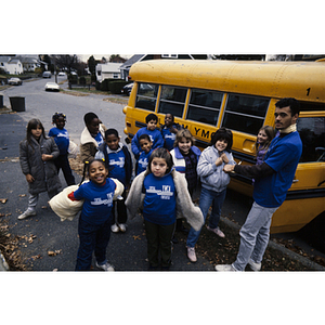 Children and group leader posing outside Waltham school bus