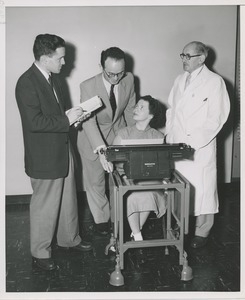 Woman demonstrating her use of a typewriter for three onlookers