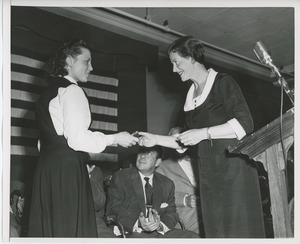 Unidentified staff member handing gift to client on stage at Institute Day