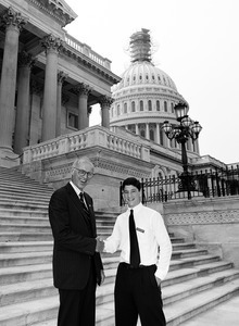 Congressman John W. Olver shaking hand with a visitor, posed on the steps of the United States Capitol building (scaffolding on top of dome)