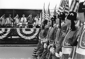 Mayor Raymond L. Flynn and others on a reviewing stand watching members of the Kora Shriners in parade